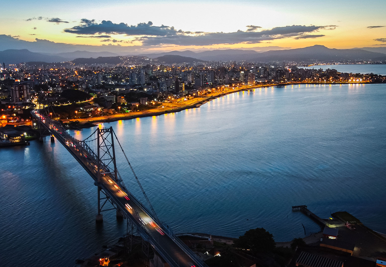 A Ponte Hercílio Luz e o Centro de Florianópolis ao anoitecer